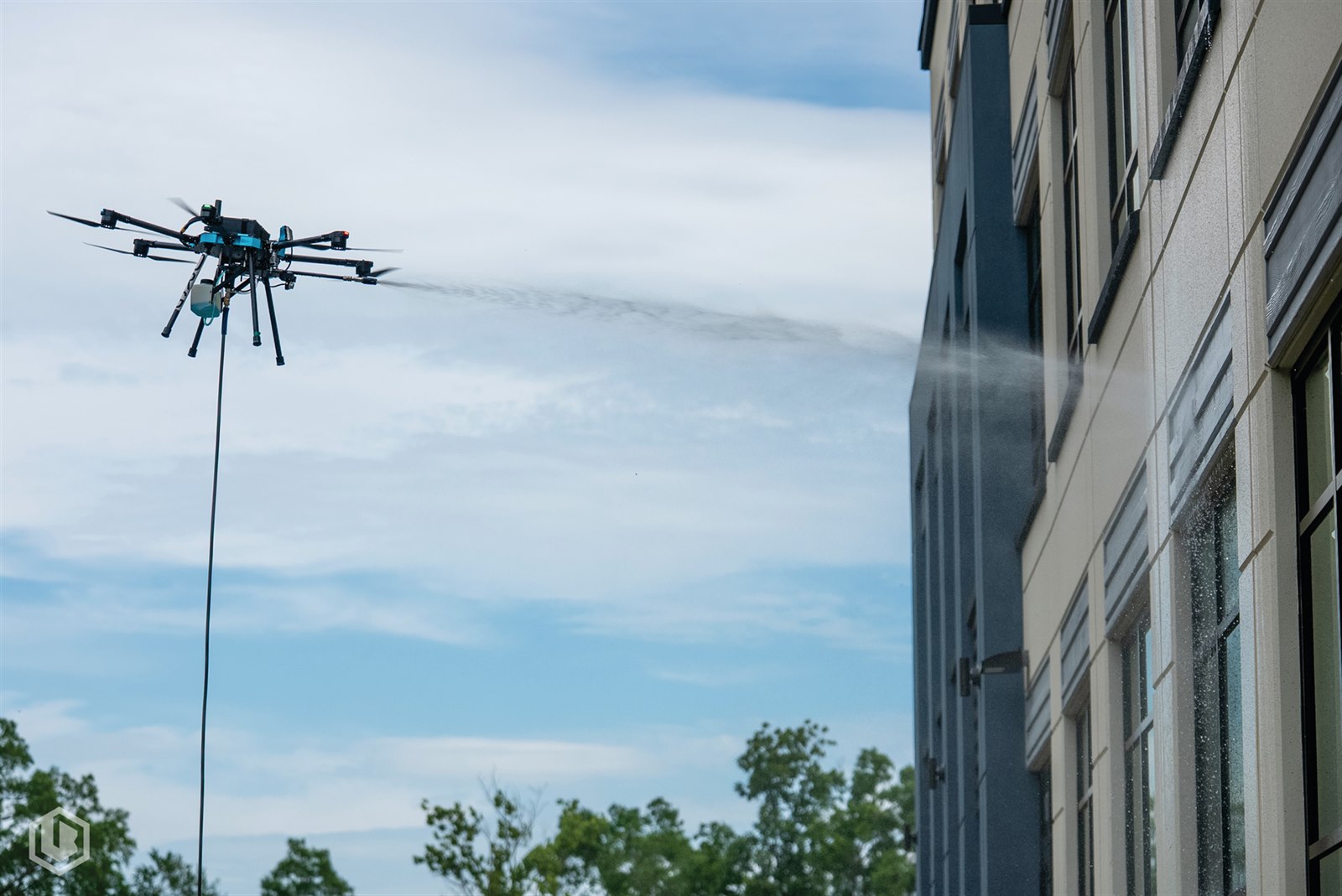 A drone spraying a multi-story building facade with water